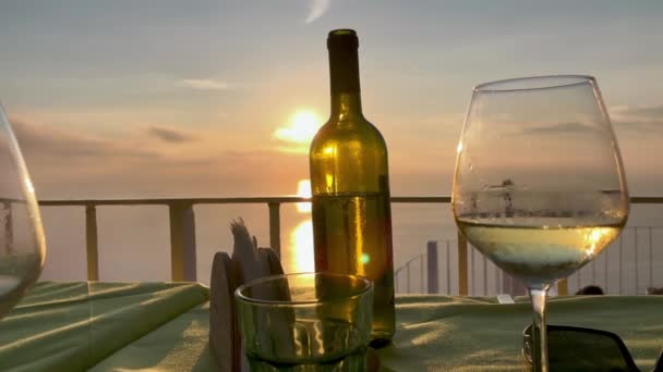 日落时分，酒杯和酒瓶，背景为全岛全景。假日概念 — 图库视频影像