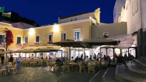 Капри, Италия - 19 июня 2021 года: Туристы и местные жители прогуливаются по знаменитой площади Пьяцццетта на закате — стоковое видео