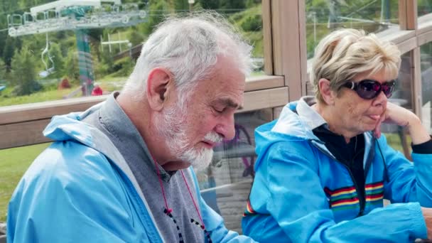 Ouderen ontspannen buiten aan een restauranttafel in een berglandschap — Stockvideo