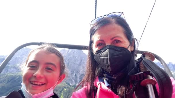 Woman and daughter on a chairlift wearing face mask — Stock Video