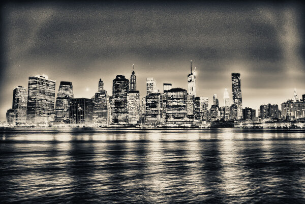 Black and white view of Manhattan skyline at night, classic view from Brooklyn Bridge Park.