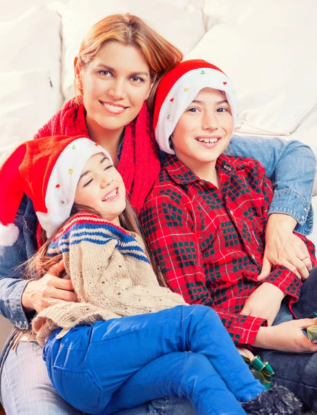 Gelukkig moeder en kinderen met santa caps genieten van Kerstmis op — Stockfoto