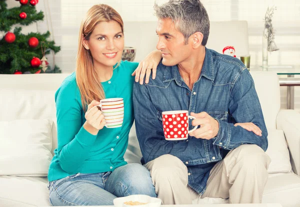 Joyeux couple de Noël buvant du thé sur le canapé de la maison avec arbre o — Photo