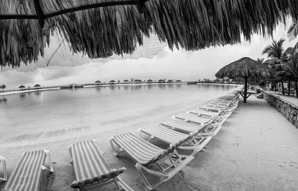 Straw umbrella and chairs on the beach of Roatan, Honduras — Stock Photo, Image