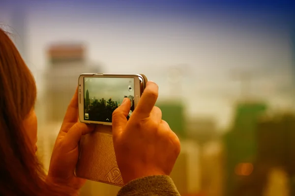 Женщина фотографирует город со своим смартфоном — стоковое фото