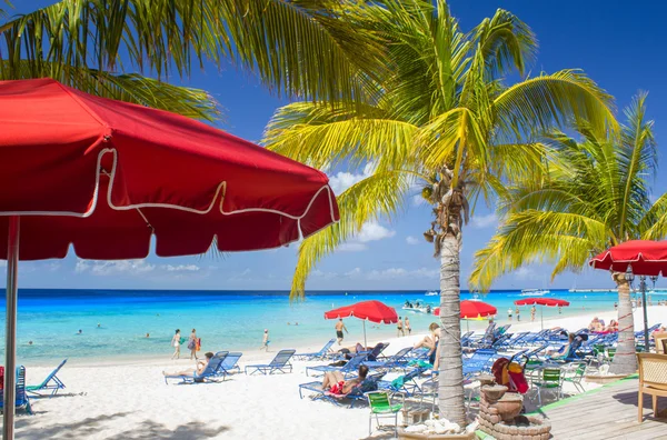 Tropical beach with relaxing people and colourful umbrellas — Stock Photo, Image