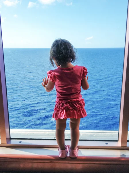 Bébé regardant par une grande fenêtre de bateau — Photo