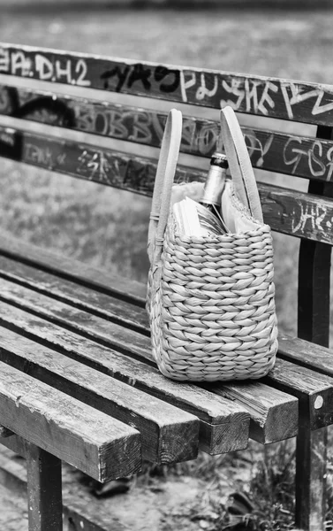 Grüne Strohtasche auf einer Parkbank — Stockfoto