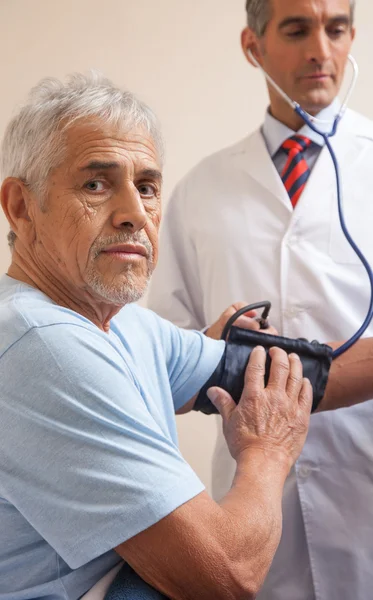 Doctor measuring  pressure to mature man — Stock Photo, Image