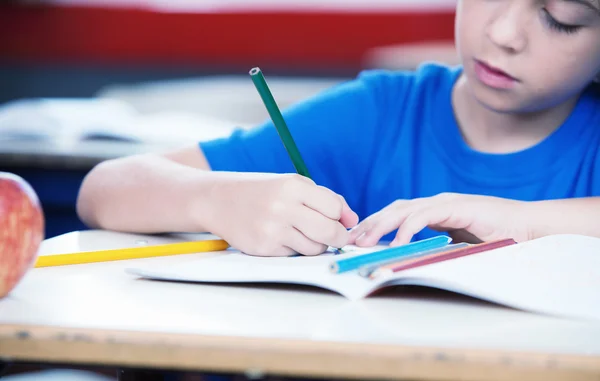 Руки ребенка в школе рисуют на его книге — стоковое фото