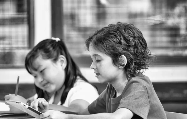 Duas crianças multirraciais usando tablet — Fotografia de Stock