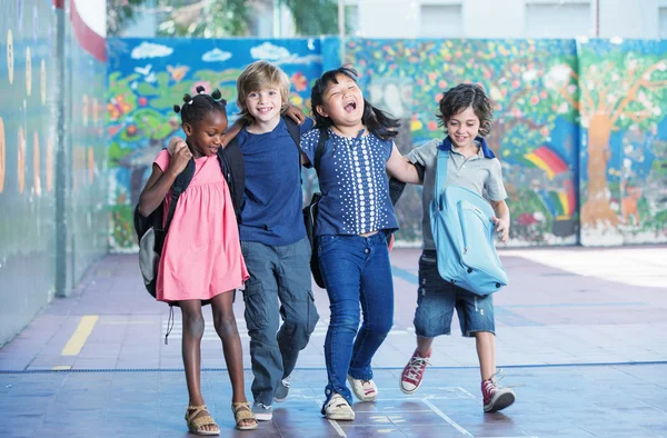 Glückliche Kinder, die sich auf dem Schulhof der Grundschule umarmen und lächeln. i — Stockfoto