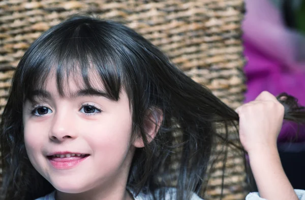 Dziecko dziewczynka dotykając włosów jednocześnie uśmiechając się — Zdjęcie stockowe