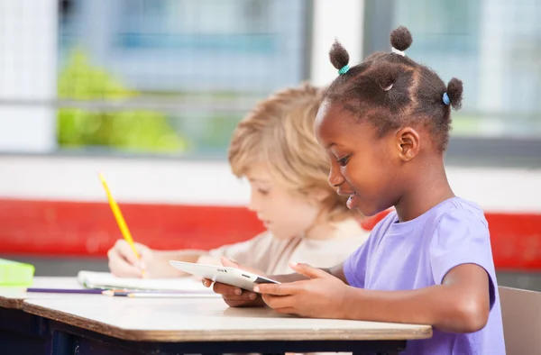 Interracial elementary classroom with students using tablet and — Stock Photo, Image