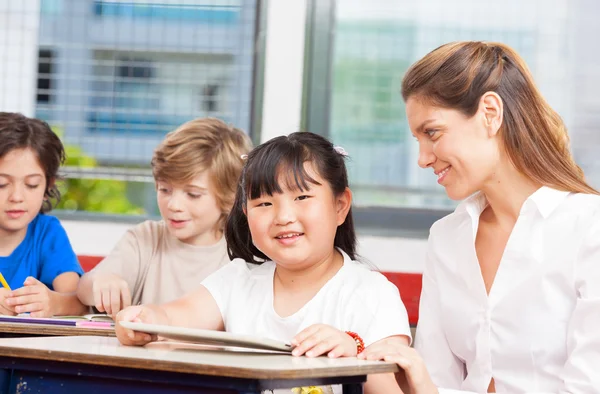 Teacher using tablet with asian student — Stock Photo, Image