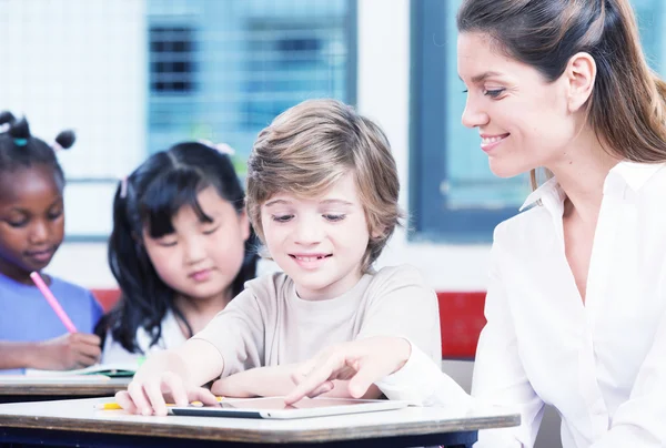 Leraar met schooljongen in een multi-etnische elementaire klas — Stockfoto