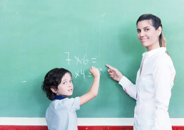 Profesora con colegial en pizarra — Foto de Stock