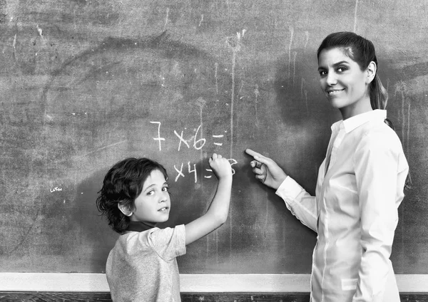 Female teacher with schoolboy at chalkboard — Stock Photo, Image