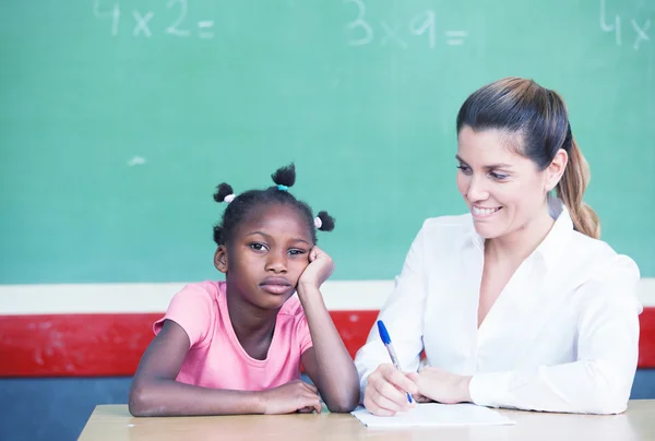 Happy female teacher comforting sad afroamerican schoolgirl