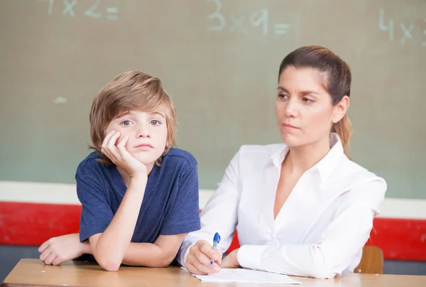 Stressé et malheureux écolier étudiant dans la salle de classe avec professeur — Photo