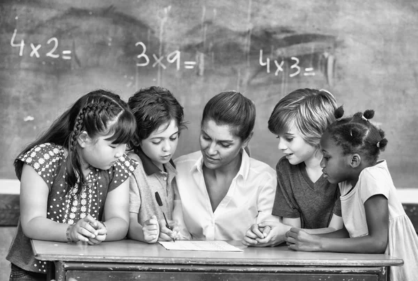 Attractive young female teacher checking multi race classroom wo — Stock Photo, Image