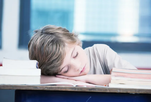 Tired child sleeping while studying in the primary school classr — Stock Photo, Image