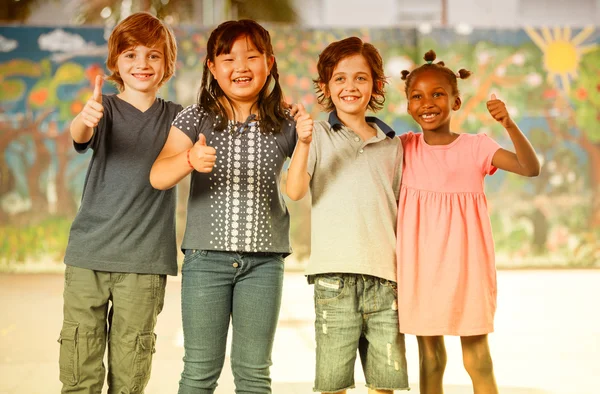 Счастливые одноклассники смешанной расы, стоящие с большими пальцами вверх — стоковое фото