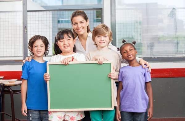 Multi-ethnic group of elementary students smiling in a classroom — Stock Photo, Image