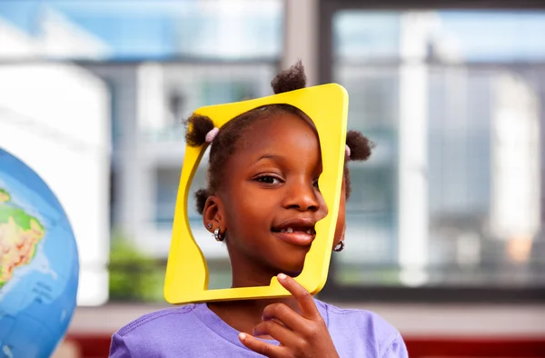 African schoolgirl joking with object in primary classroom