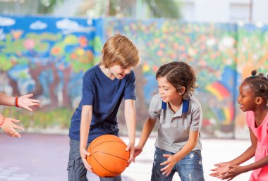 İlkokul çocuklarının okulda basketbol oynarken mutlu