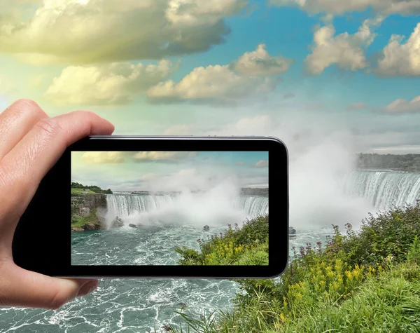 Mano femenina con smartphone tomando una foto de las Cataratas del Niágara. T — Foto de Stock