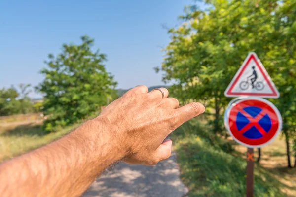 Hombre con el dedo apuntando a la señal de carretera bicicleta —  Fotos de Stock