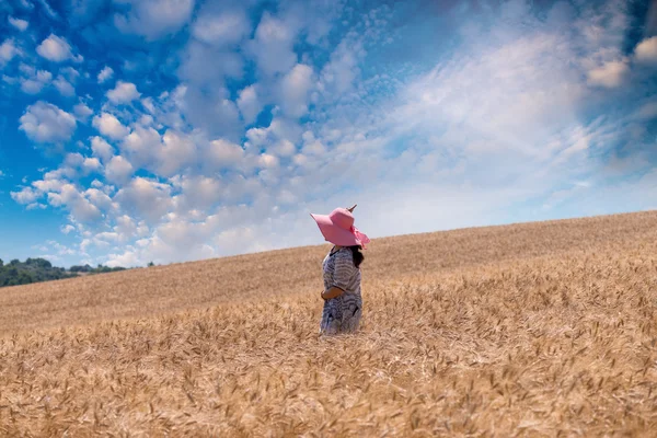 Bir buğday alanında pembe şapkalı kadın — Stok fotoğraf