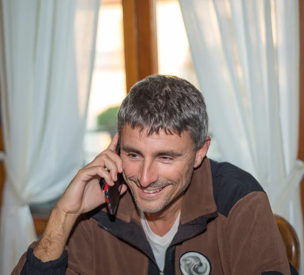 Un uomo che parla al telefono in casa sua — Foto Stock