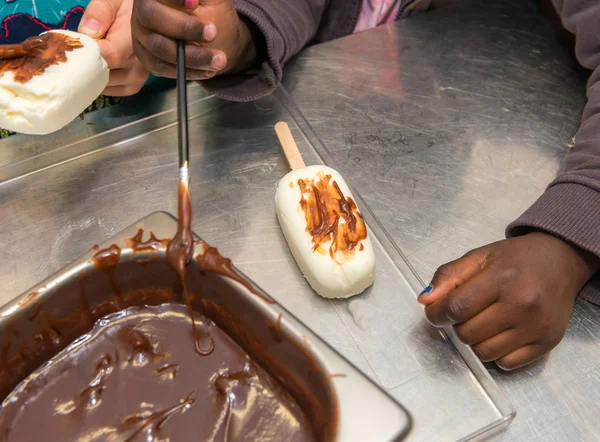 Mãos de crianças da escola primária colocando chocolate em sorvete — Fotografia de Stock