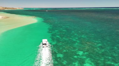 Batı Avustralya 'daki Coral Bay sahilinde turkuaz suyla seyreden bir teknenin havadan görüntüsü..