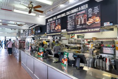 New York Şehri - 13 Haziran 2025 Nathan 'ın Coney Island fast food restoranının müşterileri ve neon ışıklarıyla iç görüntüsü. 