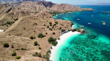 Komodo Adaları 'nın manzaralı manzarası. Pembe plaj yemyeşil tepelerle çevrili.. 