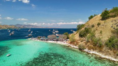 Komodo Ulusal Parkı 'ndaki Pulau Kelor' un havadan görünüşü. Küçük köpekbalıklarının yanında şnorkeller yüzüyor..
