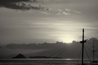 Güneş batarken etrafı tropikal renkler ve huzurlu denizlerle çevrili bir yolcu gemisinin manzarası..