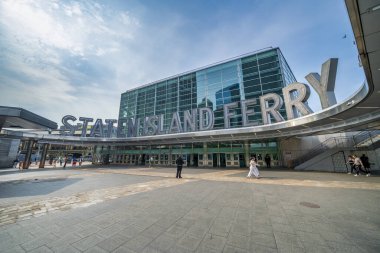 New York City - 13 Haziran 2025: Staten Island Feribot Binası dışı Parlak Terminal tabelasına giren insanlar.