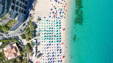 Calabria 'da turkuaz deniz ve güneş şemsiyeli Tropea plajının hava manzarası.
