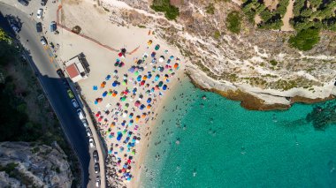 Calabria 'da turkuaz deniz ve güneş şemsiyeli Tropea plajının hava manzarası.