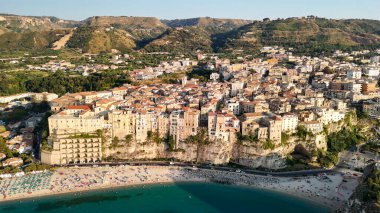 Calabria 'da turkuaz deniz ve güneş şemsiyeli Tropea plajının hava manzarası.