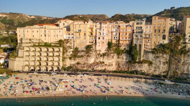 Calabria 'da turkuaz deniz ve güneş şemsiyeli Tropea plajının hava manzarası.