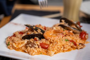 Zarif bir restoranda beyaz bir tabakta servis edilen kremalı İtalyan pilavı..