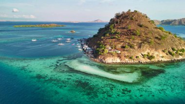 Pulau Kukusan Komodo 'nun insansız hava aracı panoraması yemyeşil adayı ve okyanusu gösteriyor..