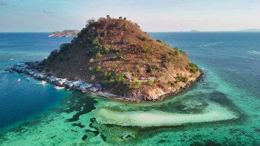 Pulau Kukusan Komodo 'nun insansız hava aracı panoraması yemyeşil adayı ve okyanusu gösteriyor..