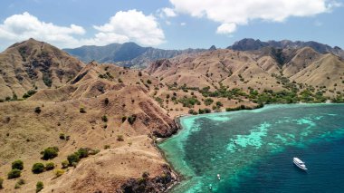 Komodo Adaları 'nın manzaralı manzarası. Pembe plaj yemyeşil tepelerle çevrili.. 