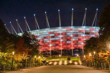 Varşova Stadyumu 'nun gece manzarası. Önünde parlak ışıklar ve plaza var..